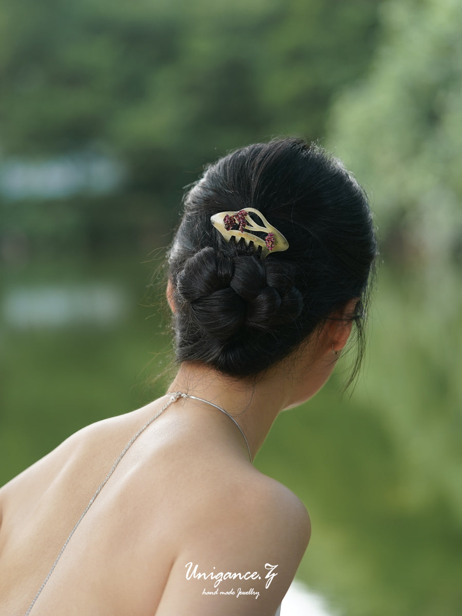 Crimson Bloom Branch Hair Comb — Person with a hair clip in their bun against a blurred green background