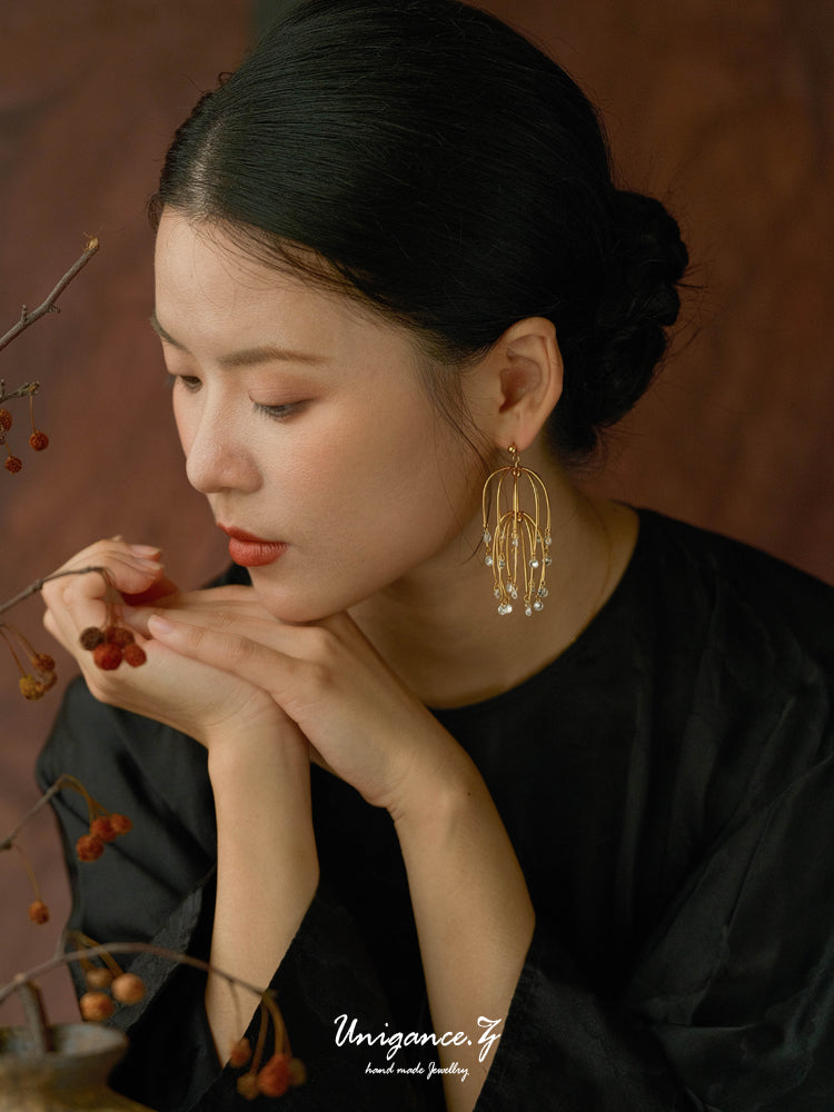 Drooping Begonia Drop Earrings — Woman wearing gold hoop earrings with a blurred background