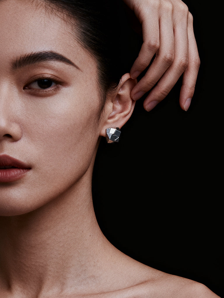 Close-up of a woman wearing a sculptural earring with a black background