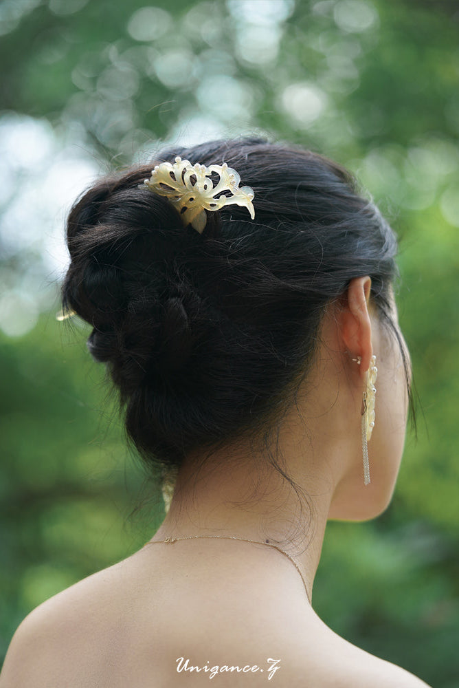 Person with elegant hair bun and floral hair accessory against a blurred green background