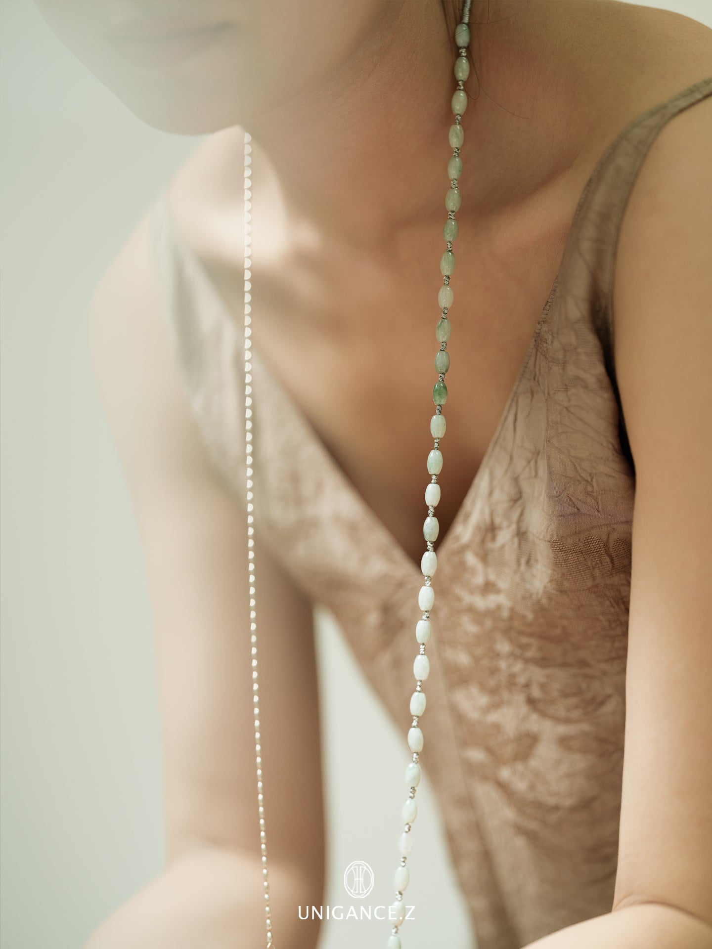 Close-up of a person wearing a delicate necklace with a neutral background