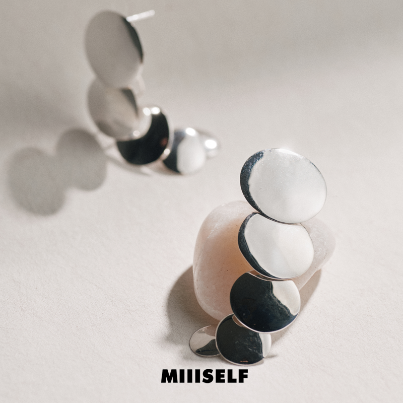 Endless Circle Disc Silver Earrings — Pair of earrings with circular design on a light gray background, featuring the brand