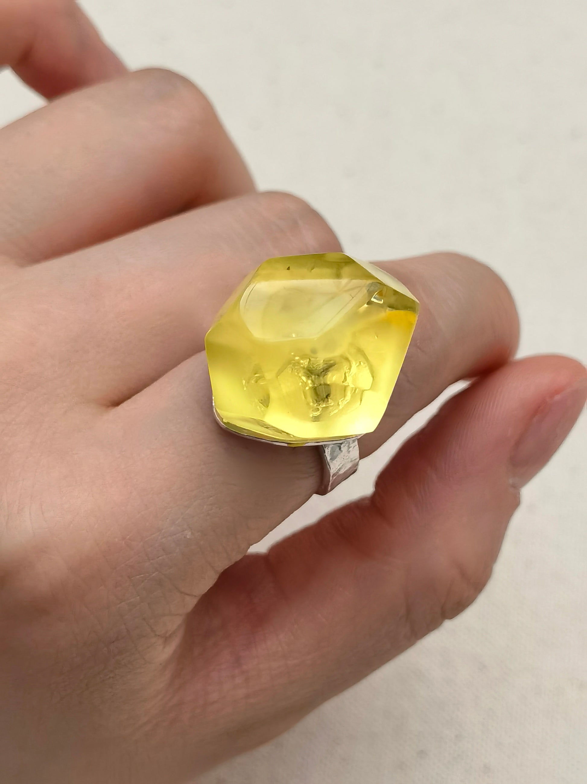 Faceted golden amber ring set in 925 sterling silver, highlighting layered inclusions and soft translucence.