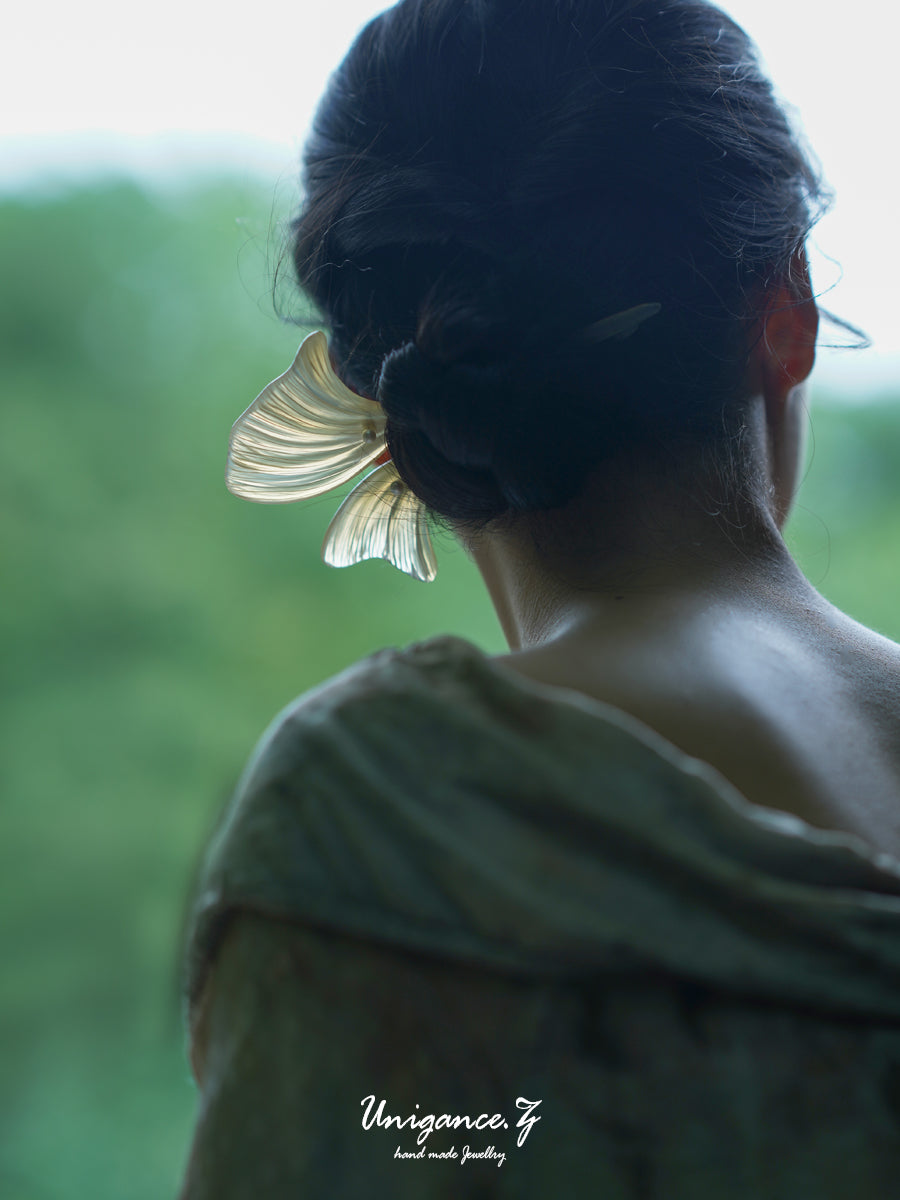 Person wearing a large butterfly hair clip with a blurred green background