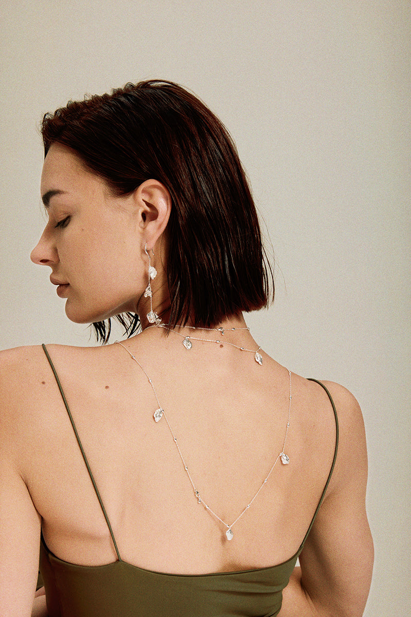Flora & Blossom Long Earrings — Woman wearing a delicate necklace with a neutral background