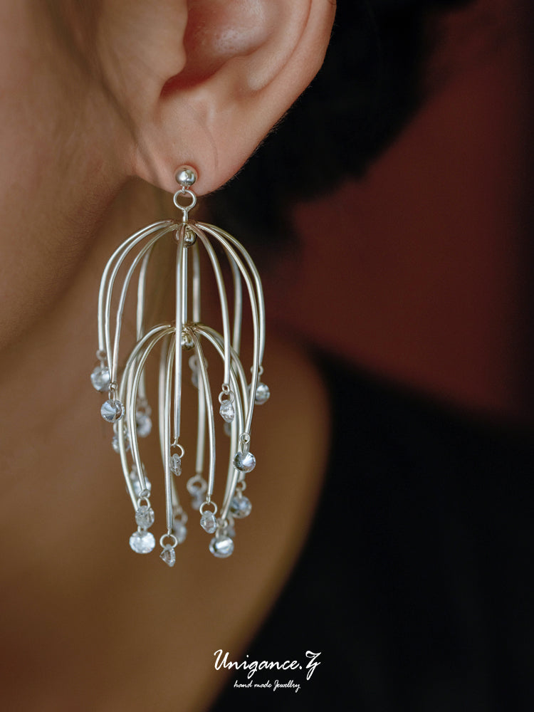 Silver earrings with beads worn by a person, brand 'Unigance' visible