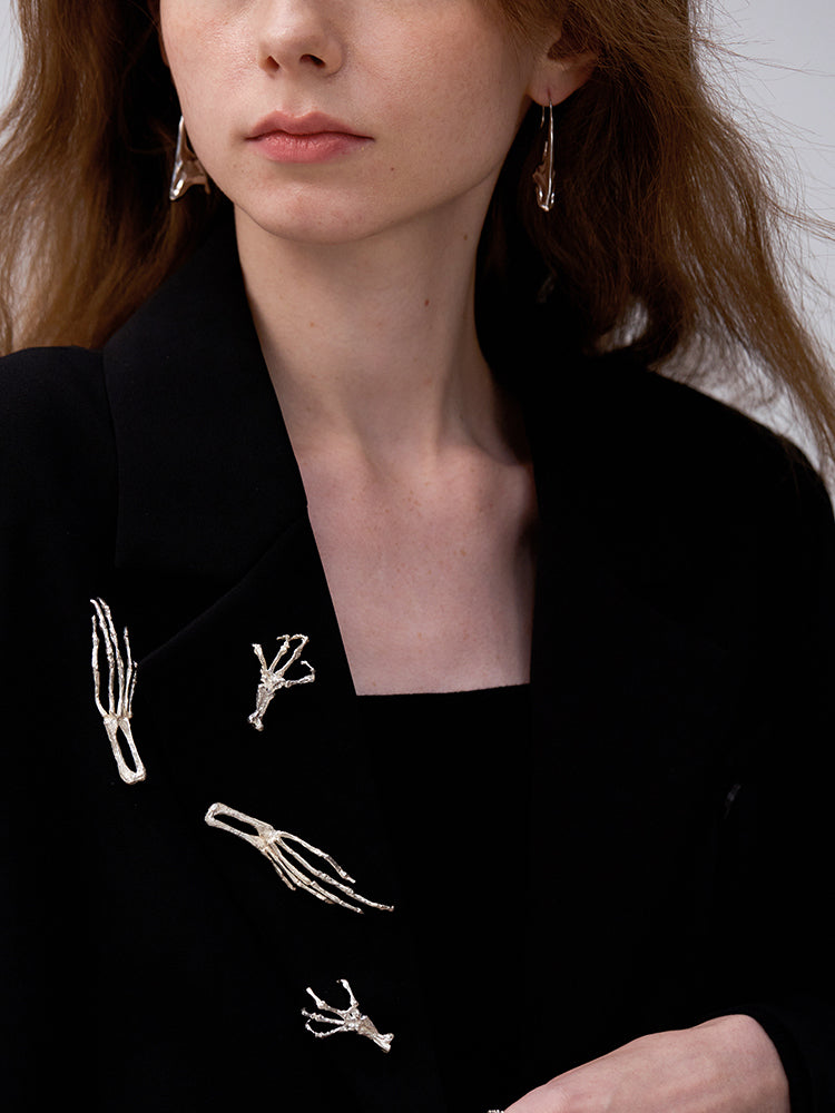 Gold Digger · Long Claw Brooch — Close-up of a person wearing a black blazer with white embroidery on a plain background