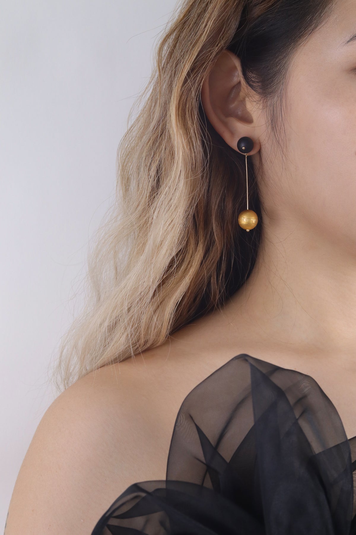 Goldfish Lacquer Quasi-Maki-e Earrings — Close-up of a person wearing a black sheer top and gold earrings with a white