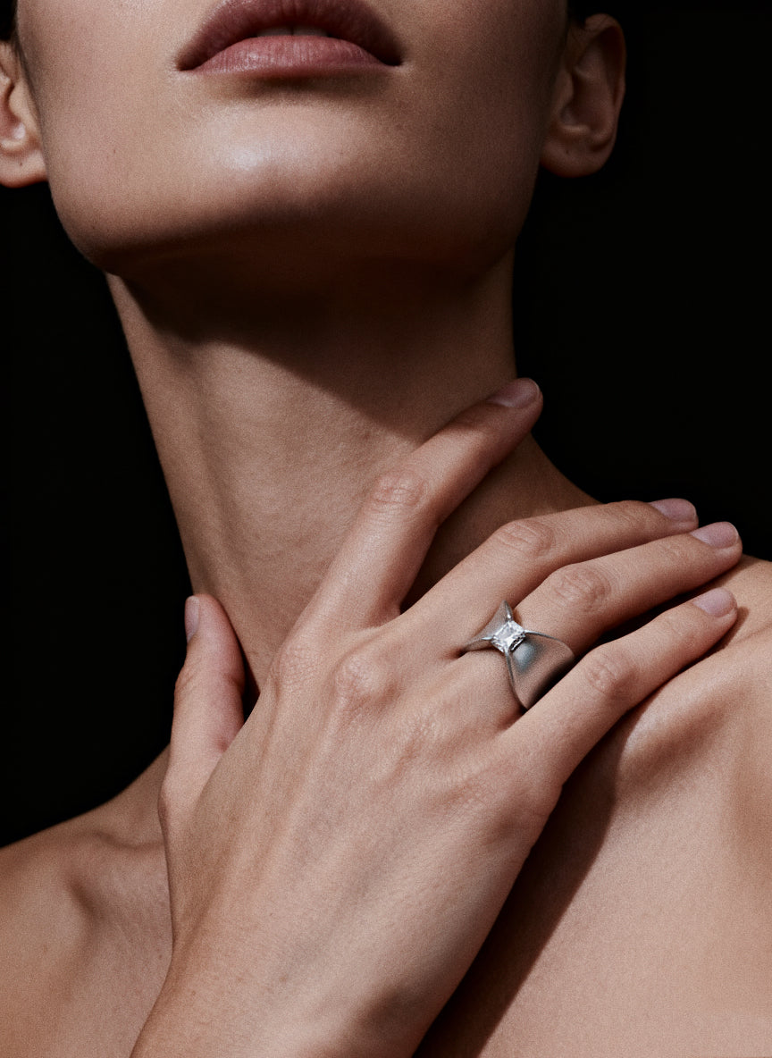 Grace Fold · Moissanite & Silver Ring — Close-up of a person wearing a silver ring on a black background