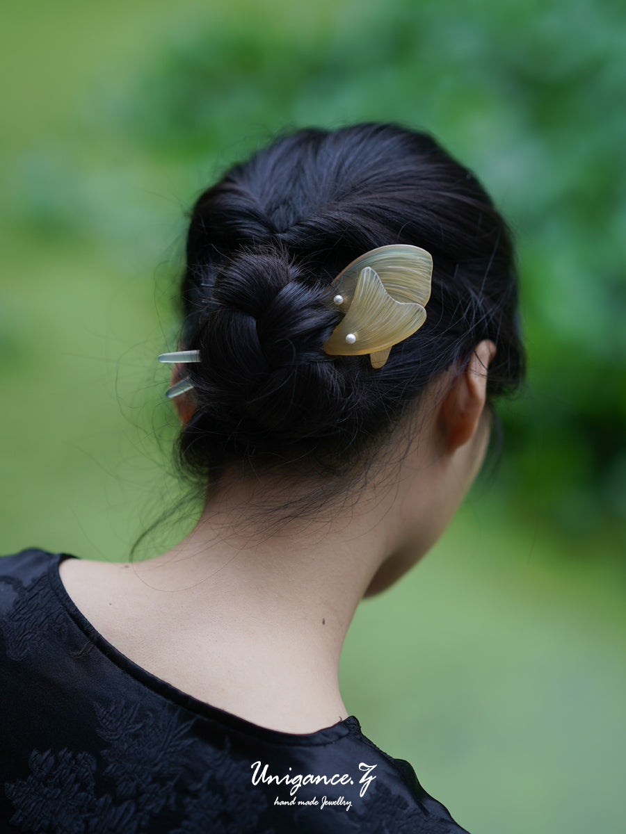 Person with a decorative hair clip in their hair against a blurred green background