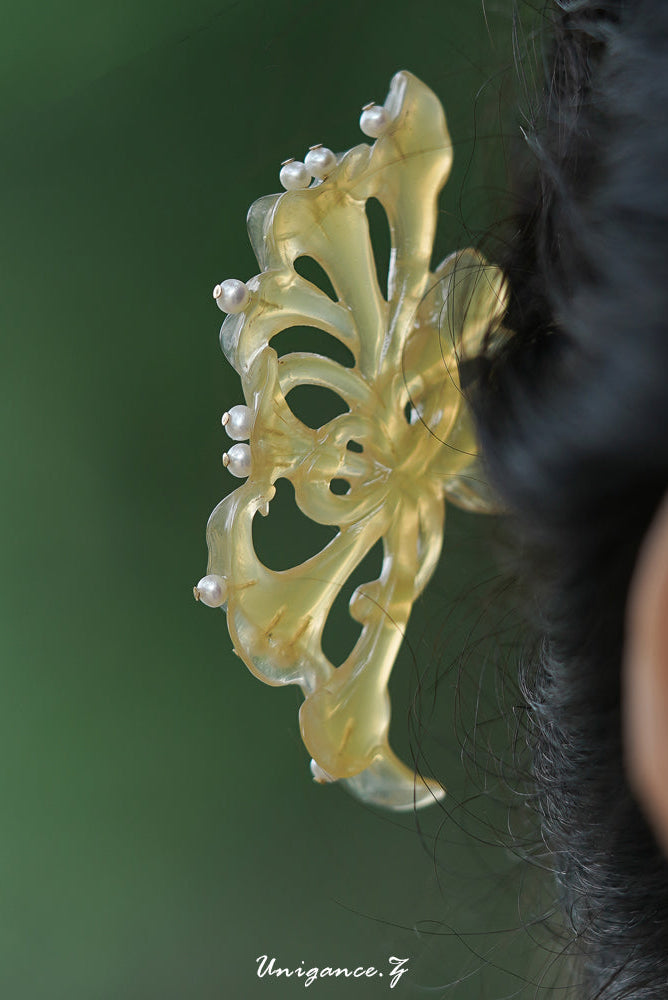 Decorative hair clip with butterfly design and pearls on a blurred background