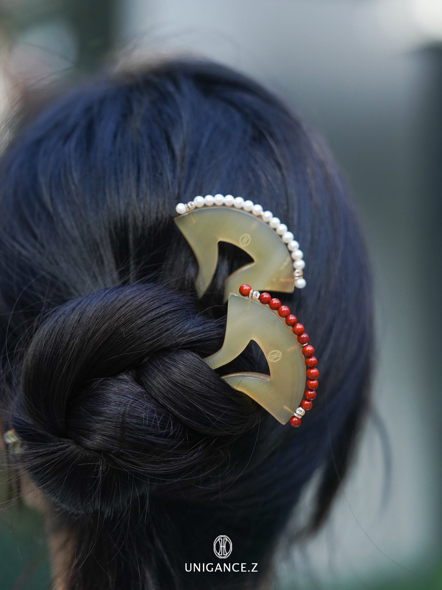 Hair accessory with gold crescent shape and red beads on a braided hairstyle, brand 'UNIGANCE.Z' visible.