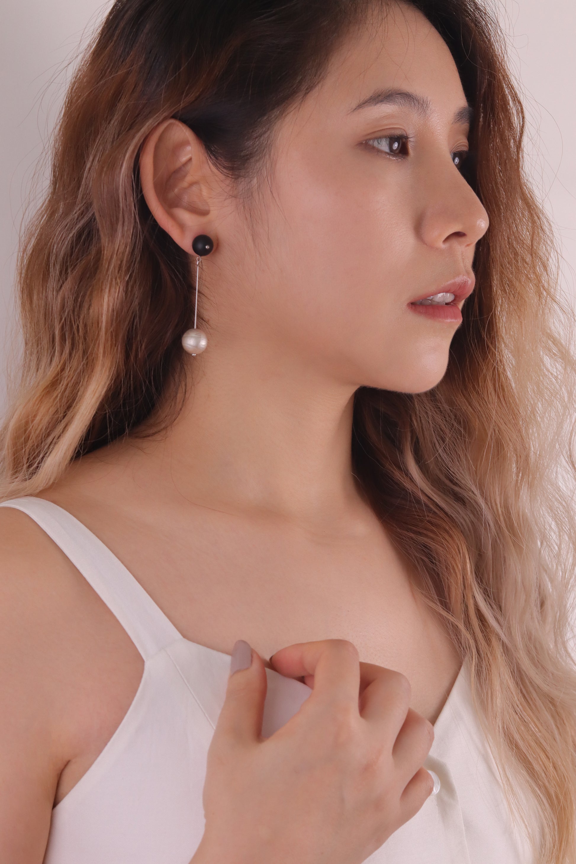 Woman wearing pearl earrings with a plain background
