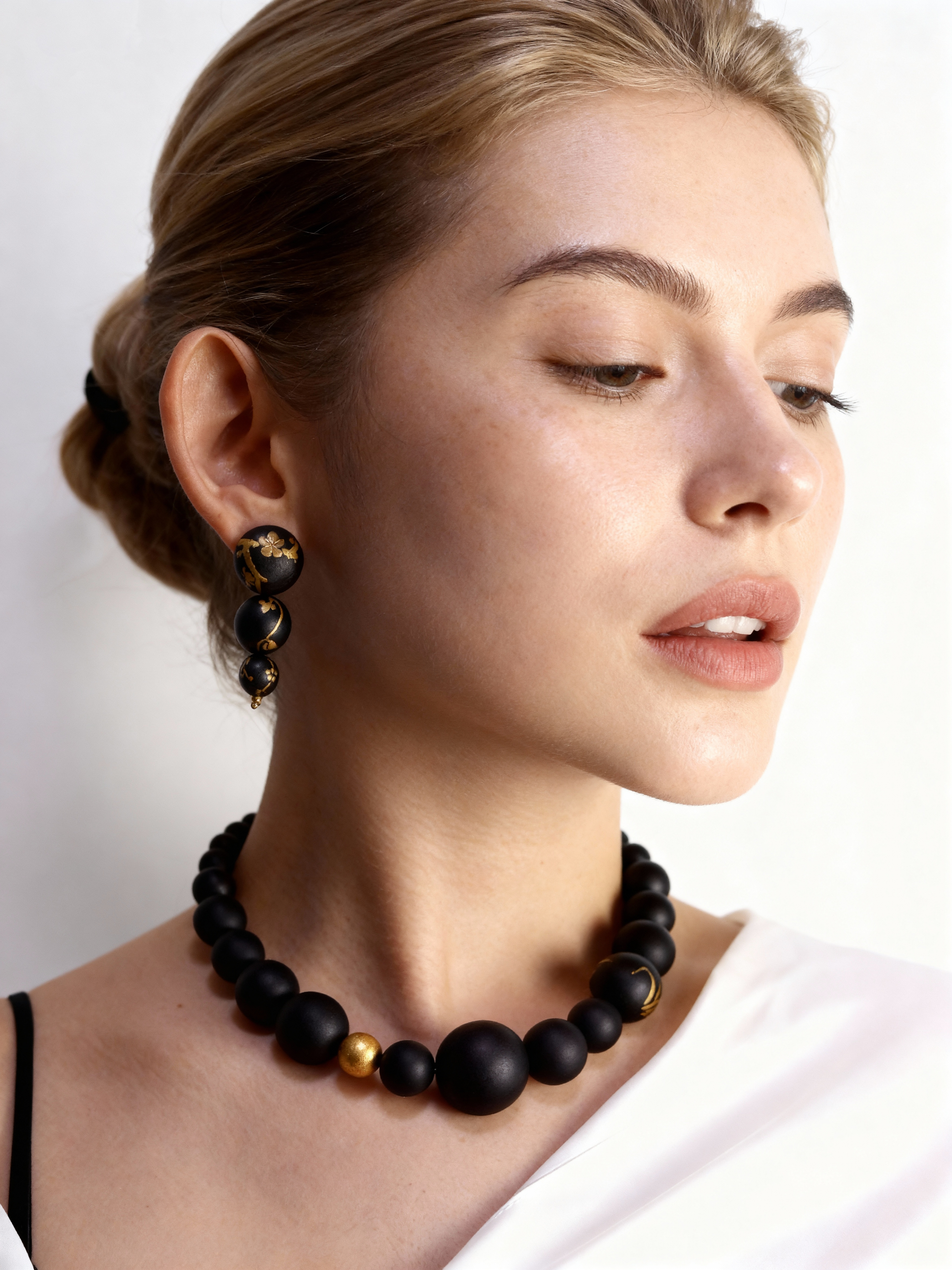 Woman wearing a black beaded necklace and earrings on a plain background