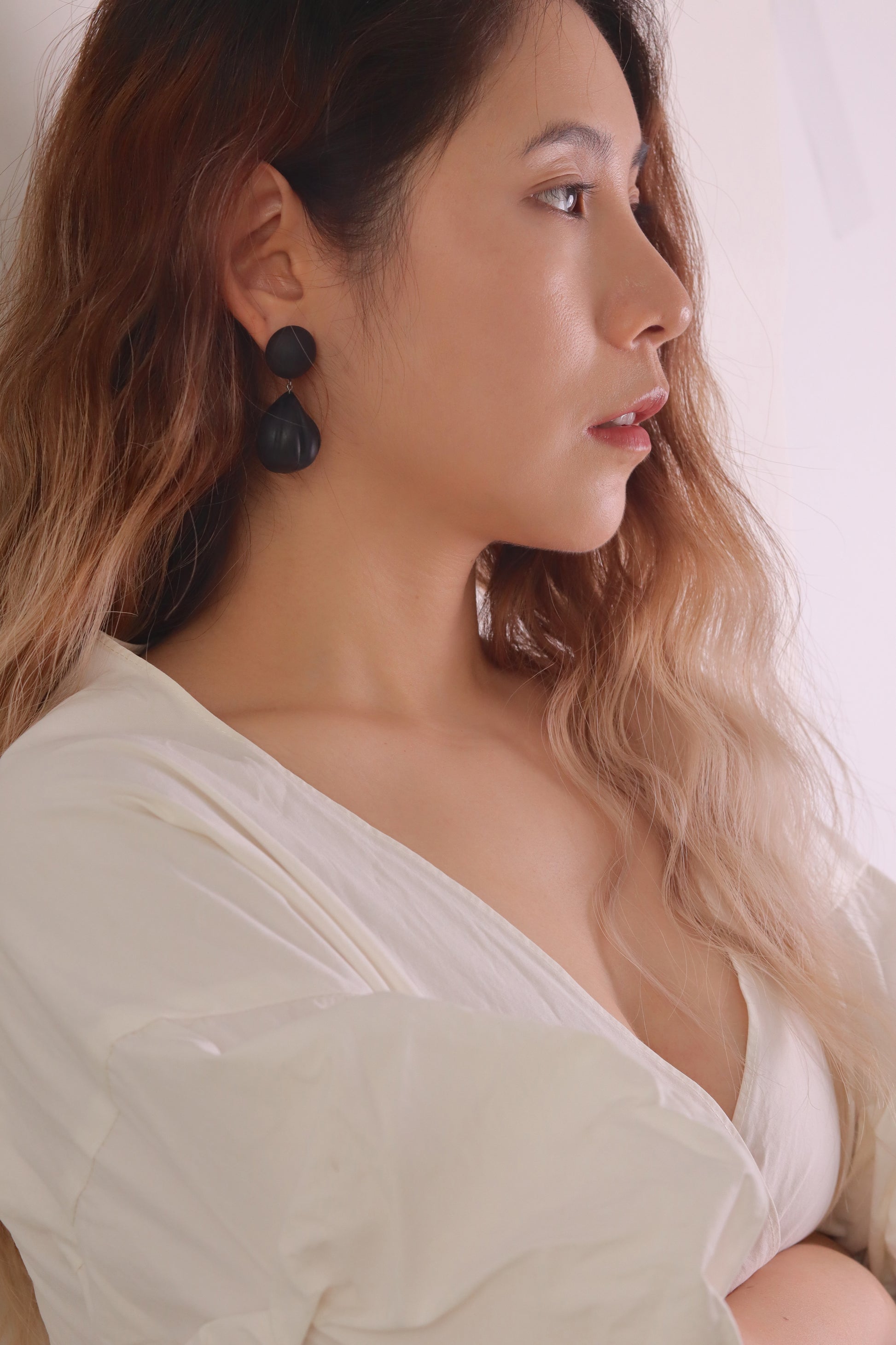 Woman wearing black earrings with a plain background
