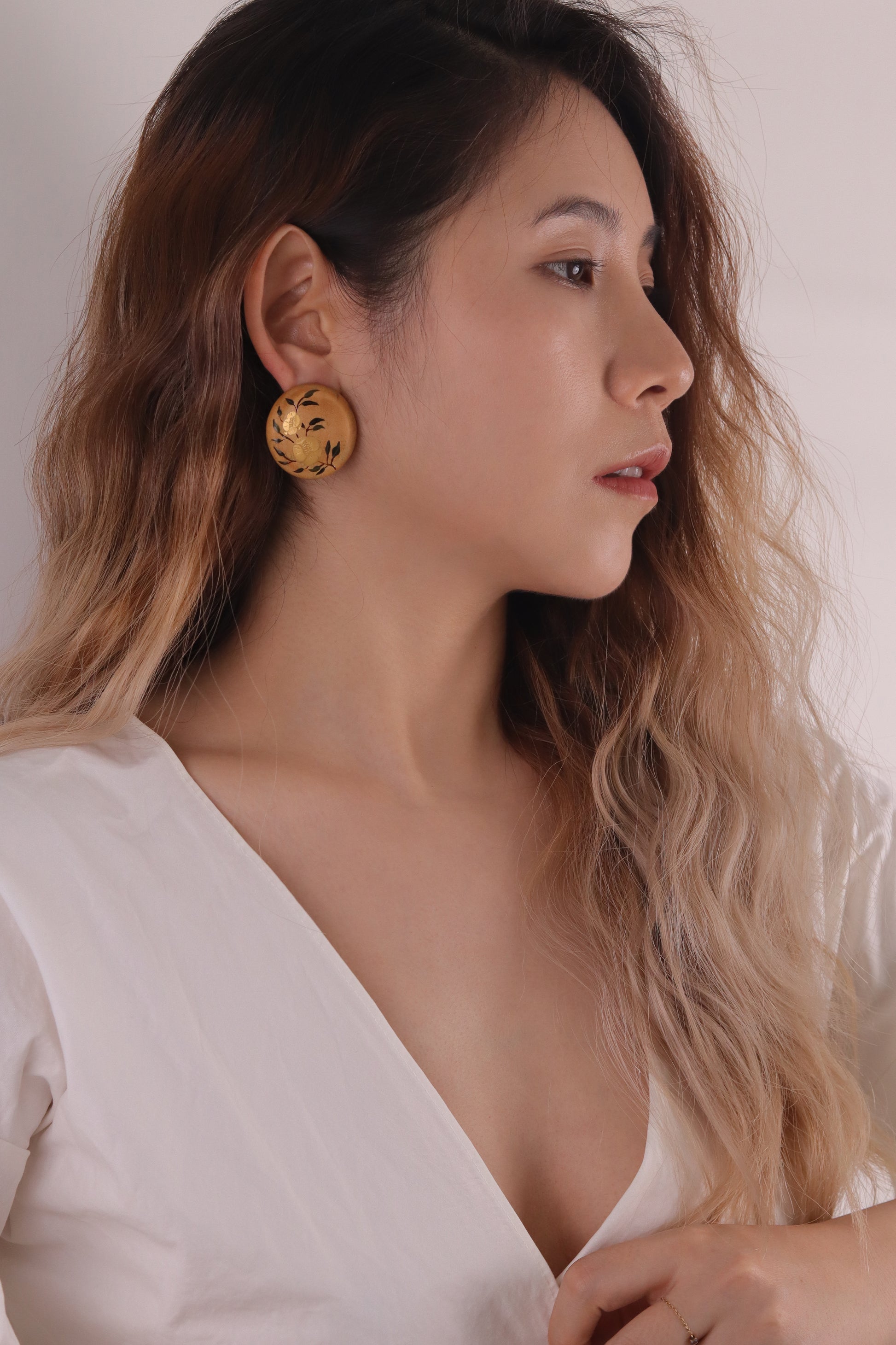 Woman wearing gold earrings with a plain background