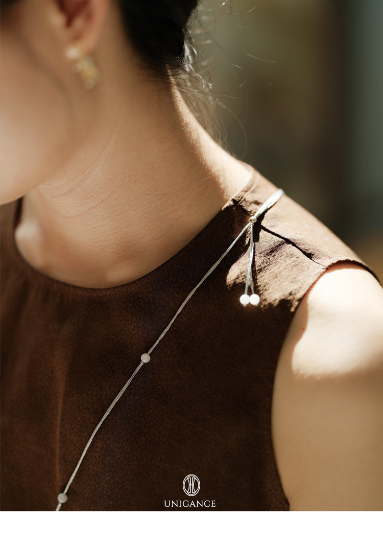 Close-up of a person wearing a delicate necklace with a blurred background