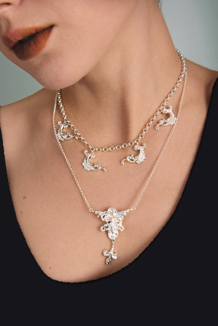 Close-up of a person wearing a silver necklace with intricate designs.