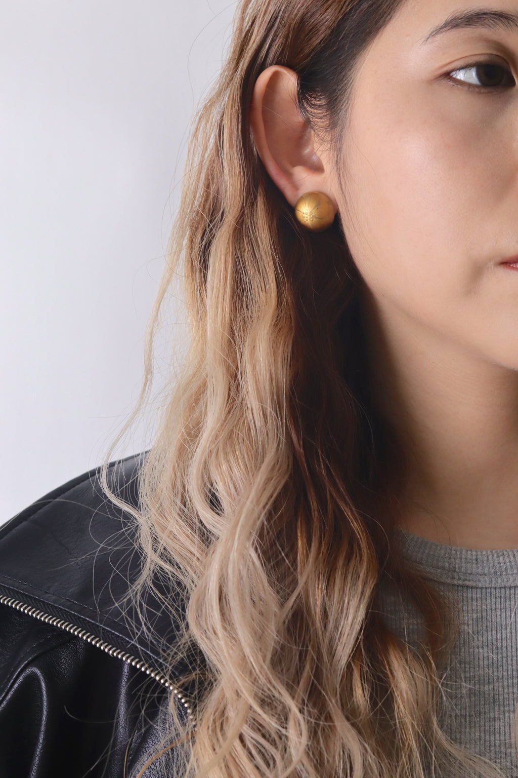 Hibiscus Quasi-Maki-e Earrings — Close-up of a person wearing a gold earring with a plain background
