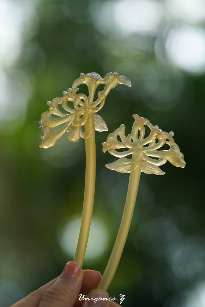 Honeysuckle Pearl Hairpin — Decorative hair sticks with floral design held against a blurred green background