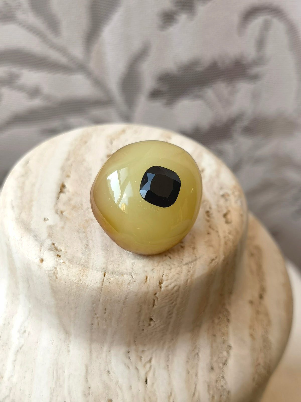 I’m Watching You · Amber & Cushion Black Spinel Brooch — Glass eye on a textured surface with a neutral background
