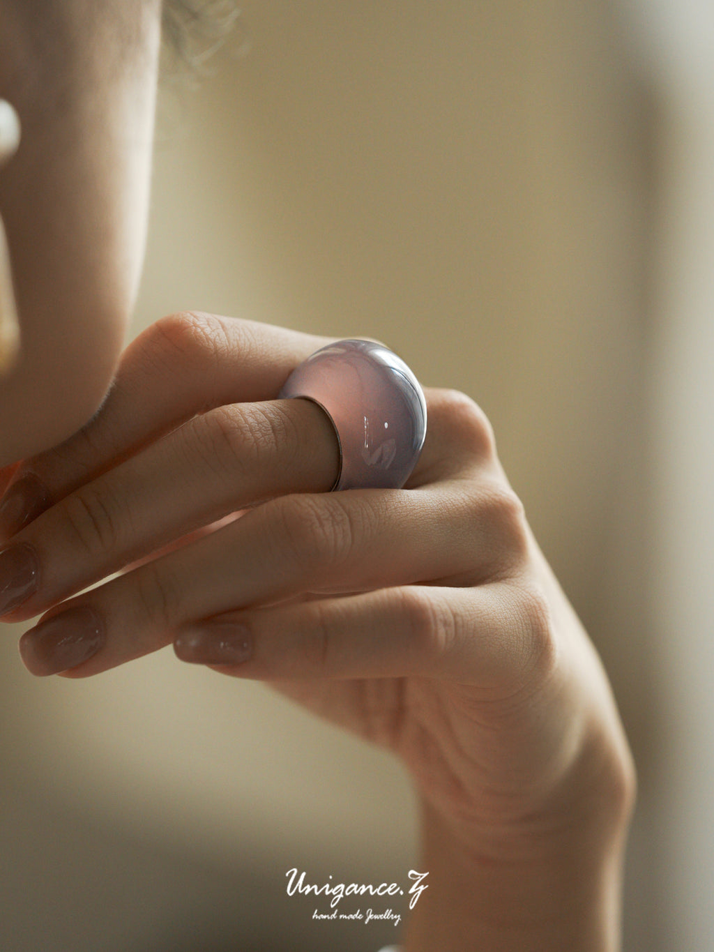 Close-up of a hand wearing a rose gold ring with a blurred background