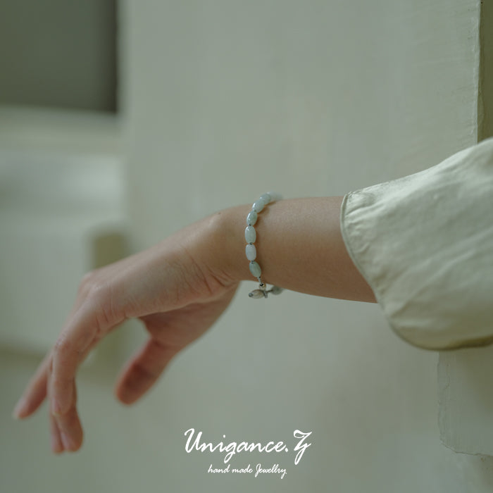 Jade Rice Bead Bracelet — Hand wearing a bracelet with a blurred background and 'Unigance' branding.