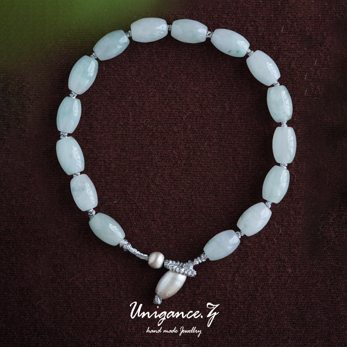 Jade Rice Bead Bracelet — Beaded necklace with light blue beads and silver accents on a dark brown background, branded