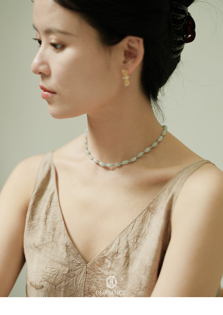 Jade Rice Bead Layered Necklace — Woman wearing a delicate necklace and earrings with a neutral background