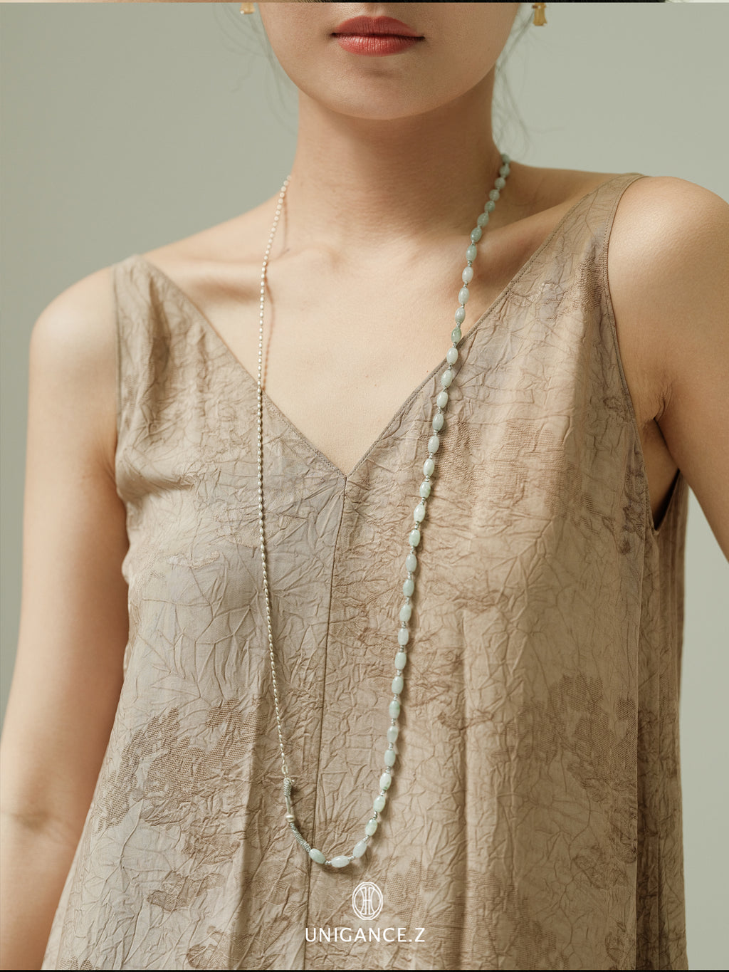 Jade Rice Bead Layered Necklace — Woman wearing a beige sleeveless top with a long necklace, brand 'UNIGANCE' visible.