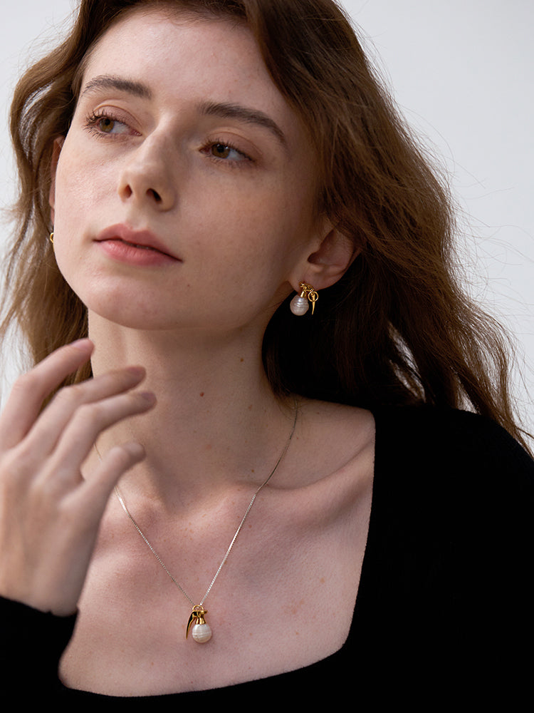 Last Gift · Grenade Pearl Necklace — Woman wearing a necklace and earrings with a plain background