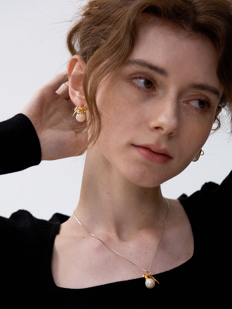 Last Gift · Grenade Pearl Necklace — Close-up of a person wearing gold earrings and a necklace with a pearl pendant.