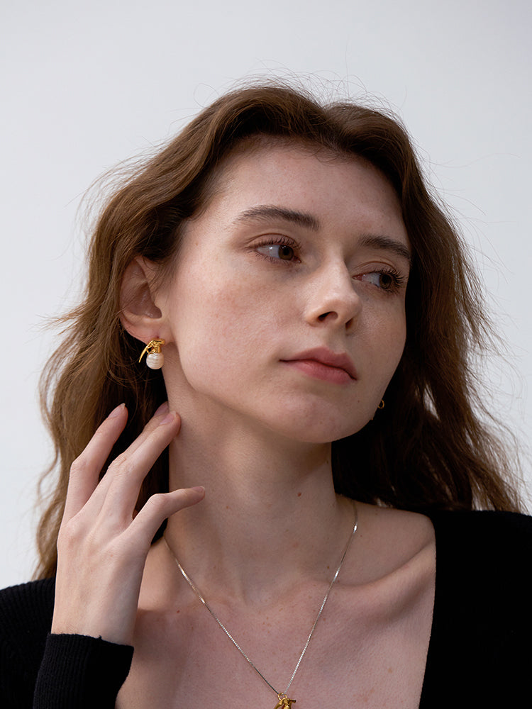 Last Gift · Grenade Pearl Stud Earrings — Woman wearing gold earrings and a necklace against a white background