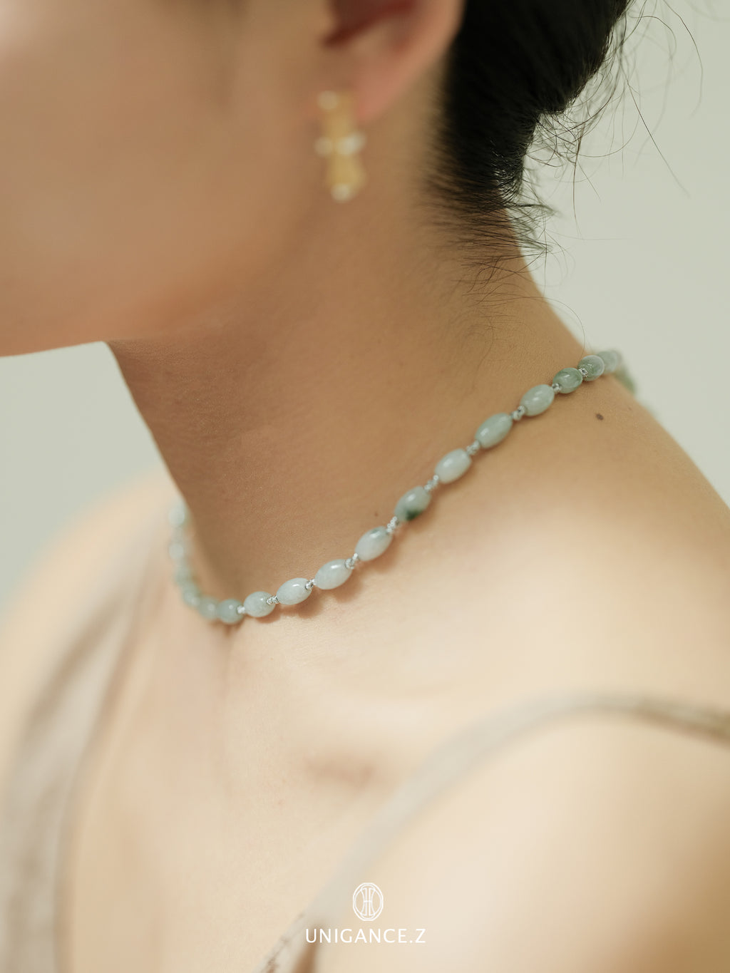 Close-up of a person wearing a light blue beaded necklace with a neutral background