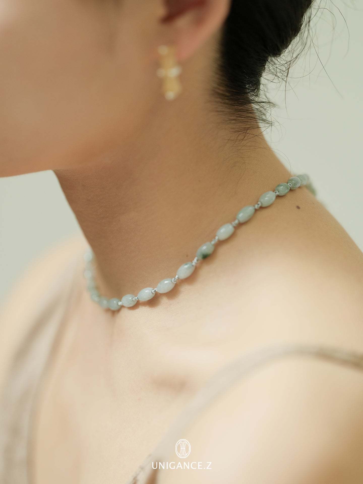 Close-up of a person wearing a light blue beaded necklace with a neutral background