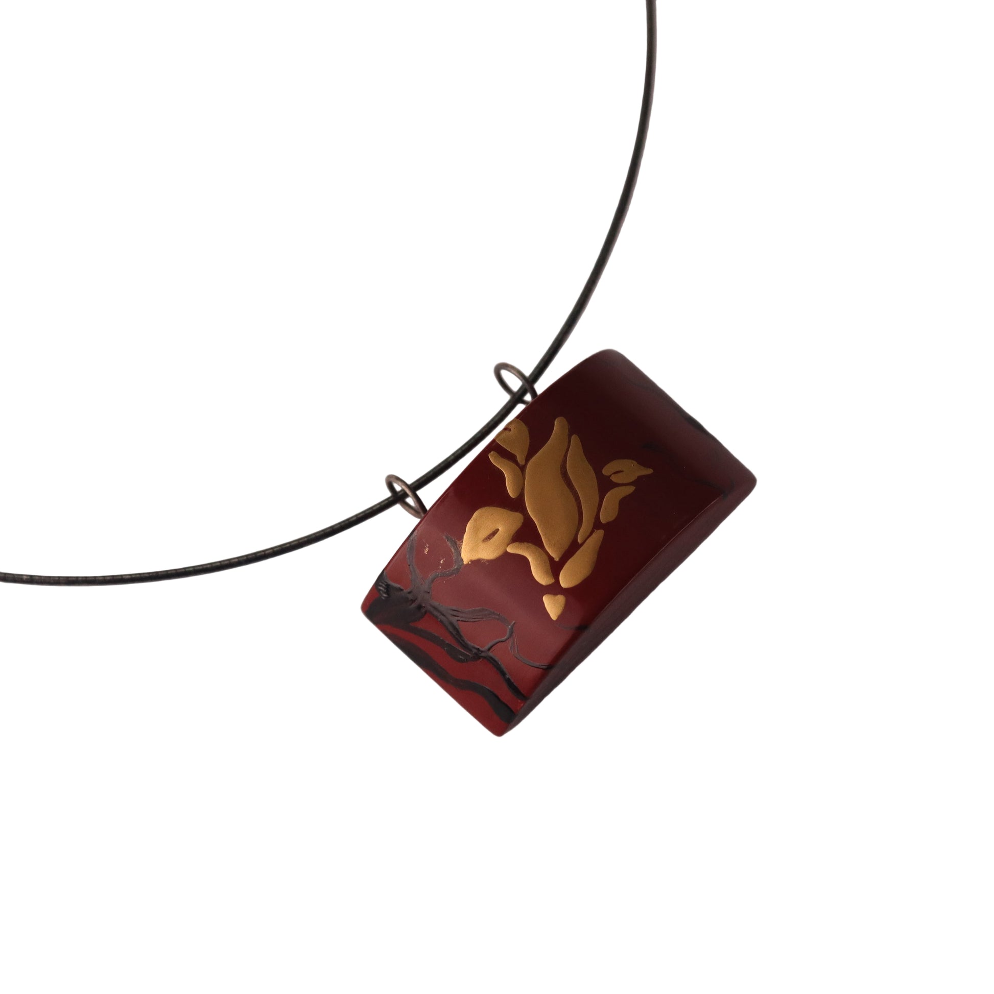 Rectangular pendant with leaf design on a black cord against a white background
