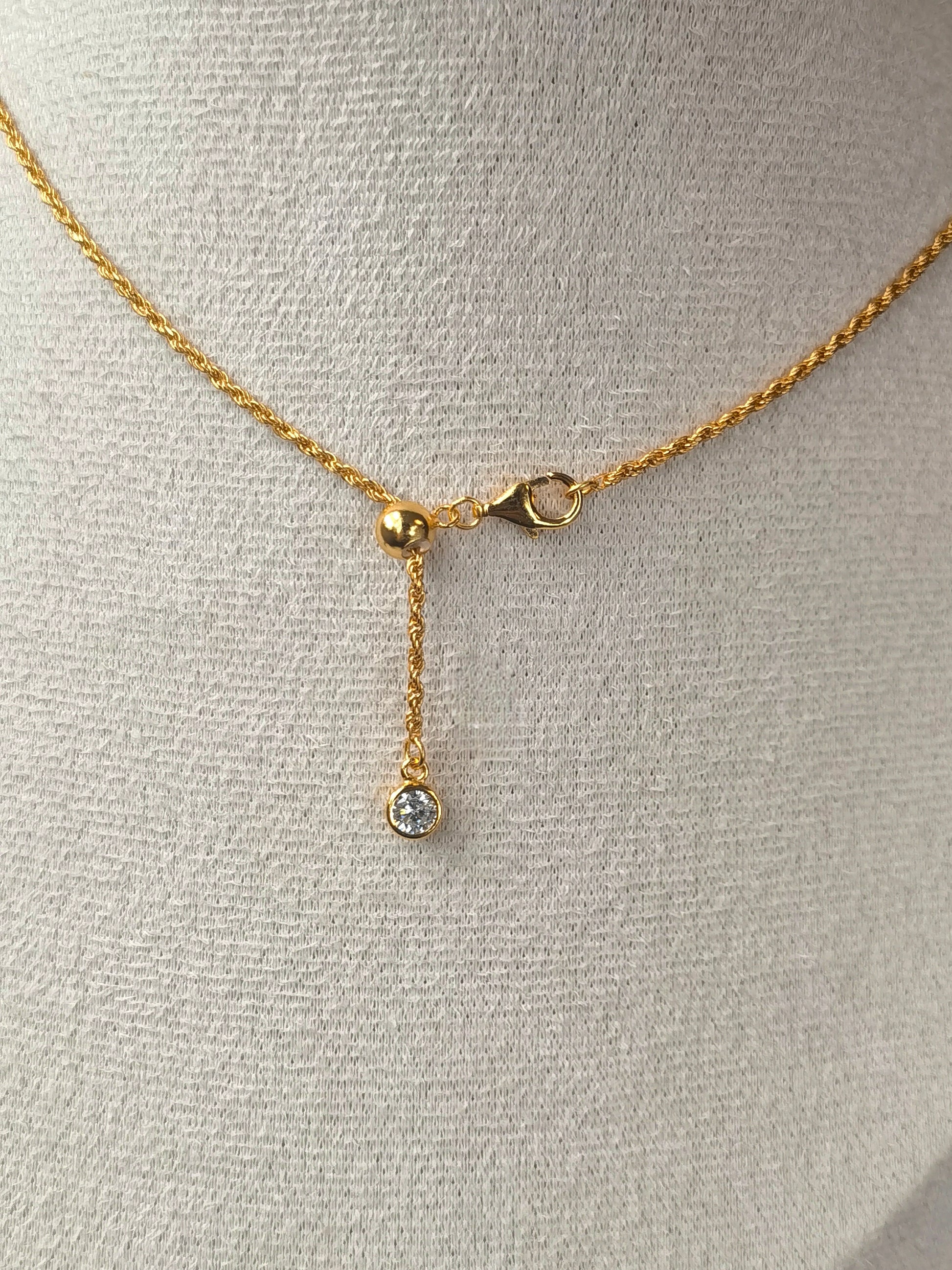 Gold necklace with a pendant on a gray mannequin bust