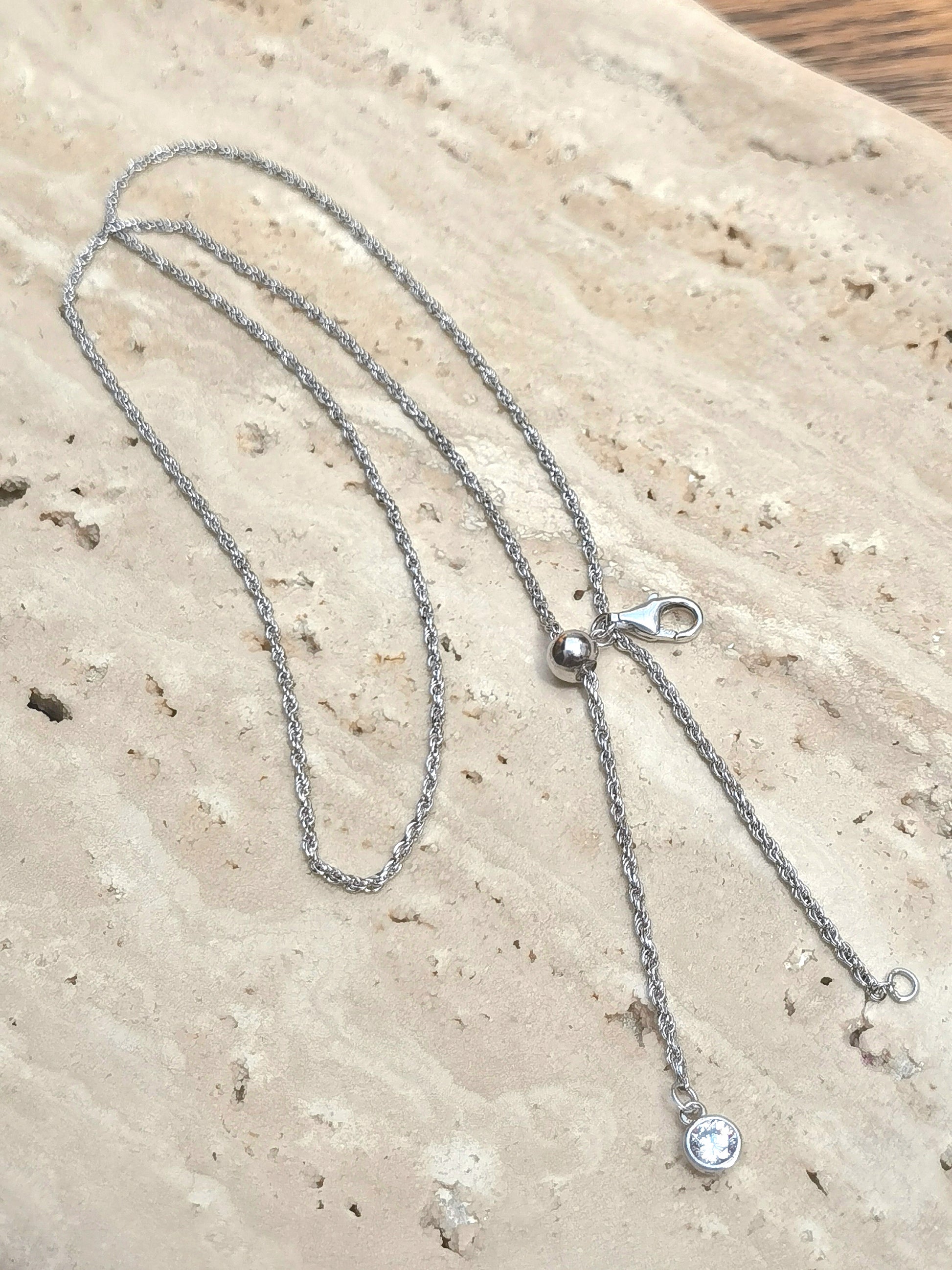 Silver necklace with a clasp on a textured beige surface
