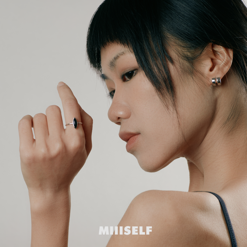 Woman wearing a ring with 'MIIISELF' branding on a neutral background