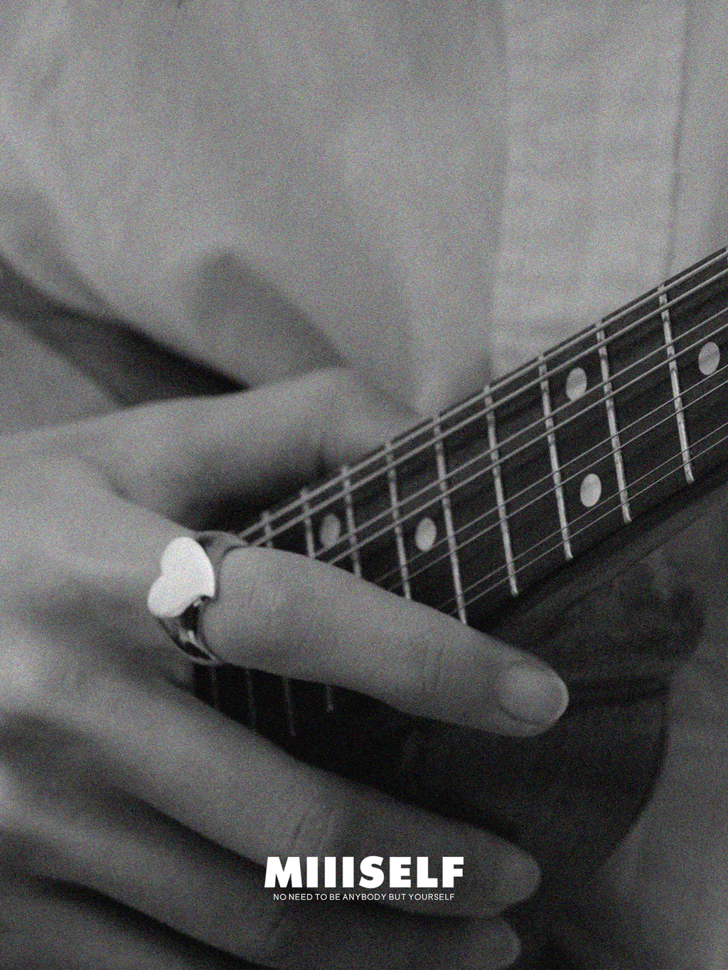 Close-up of a person playing guitar with a heart-shaped ring, featuring the brand 'Miiiself'.