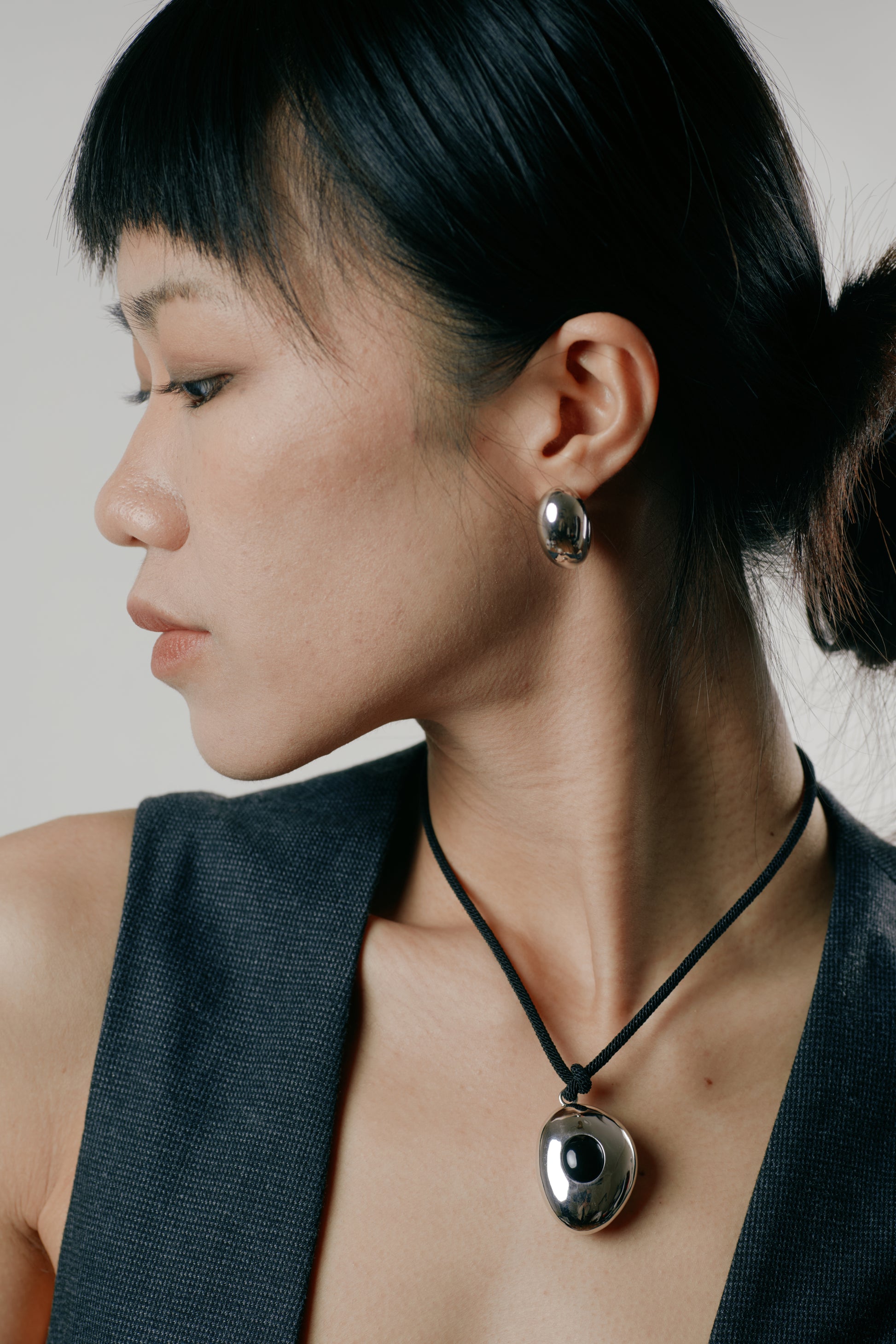 Woman wearing a necklace with a pendant against a neutral background