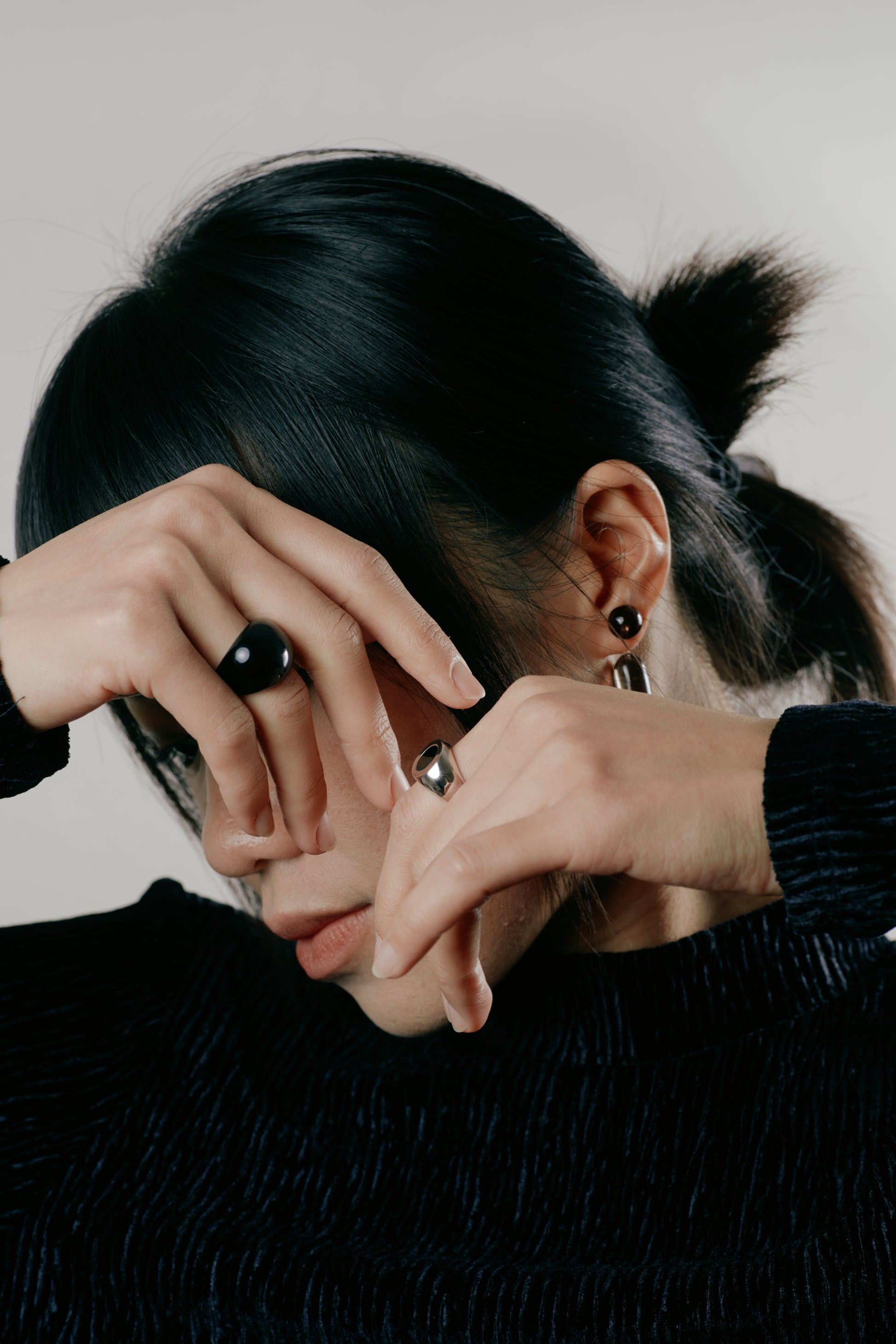 Person with hands covering face against a neutral background