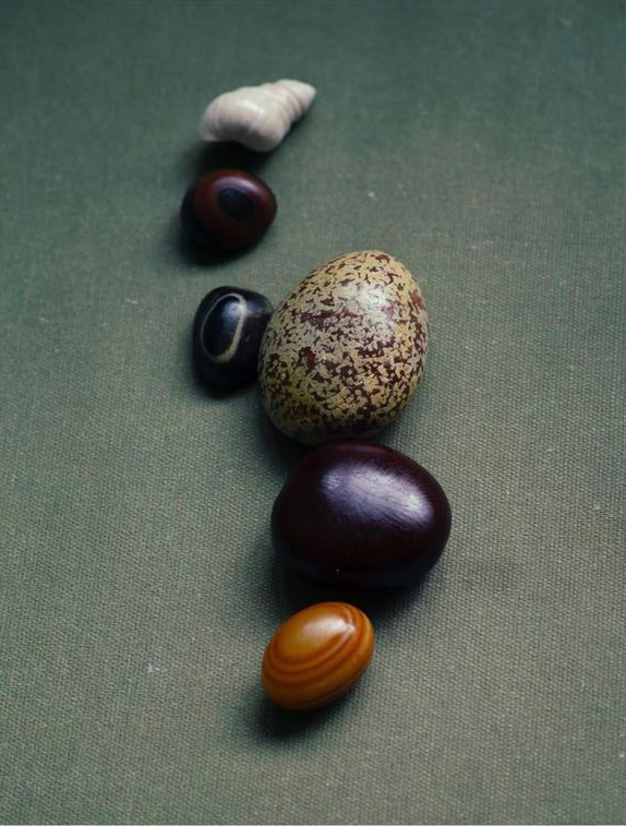 Collection of various stones and an egg on a textured surface