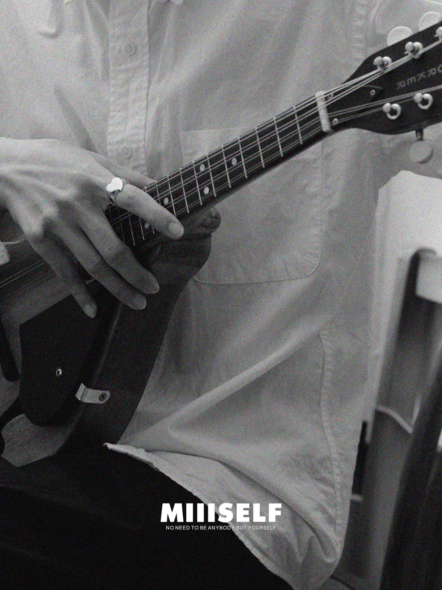 Black and white photo of a person playing an electric guitar with 'MIIISELF' branding.