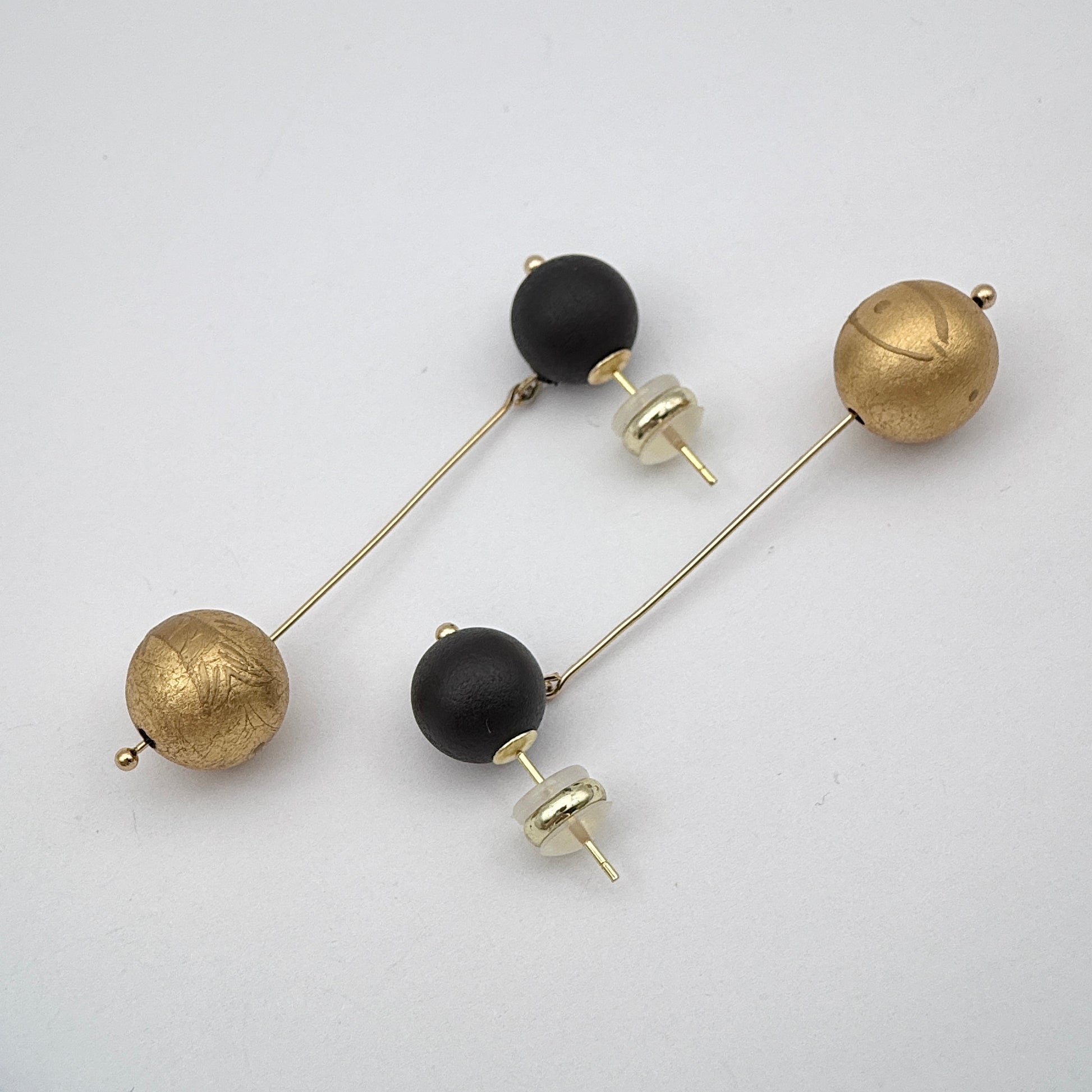 Pair of earrings with black and gold spherical beads on a white background