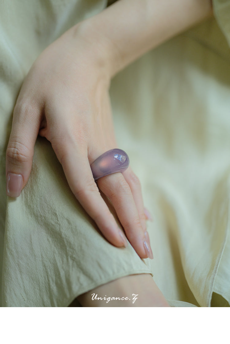 Hand wearing a purple ring on a light fabric background