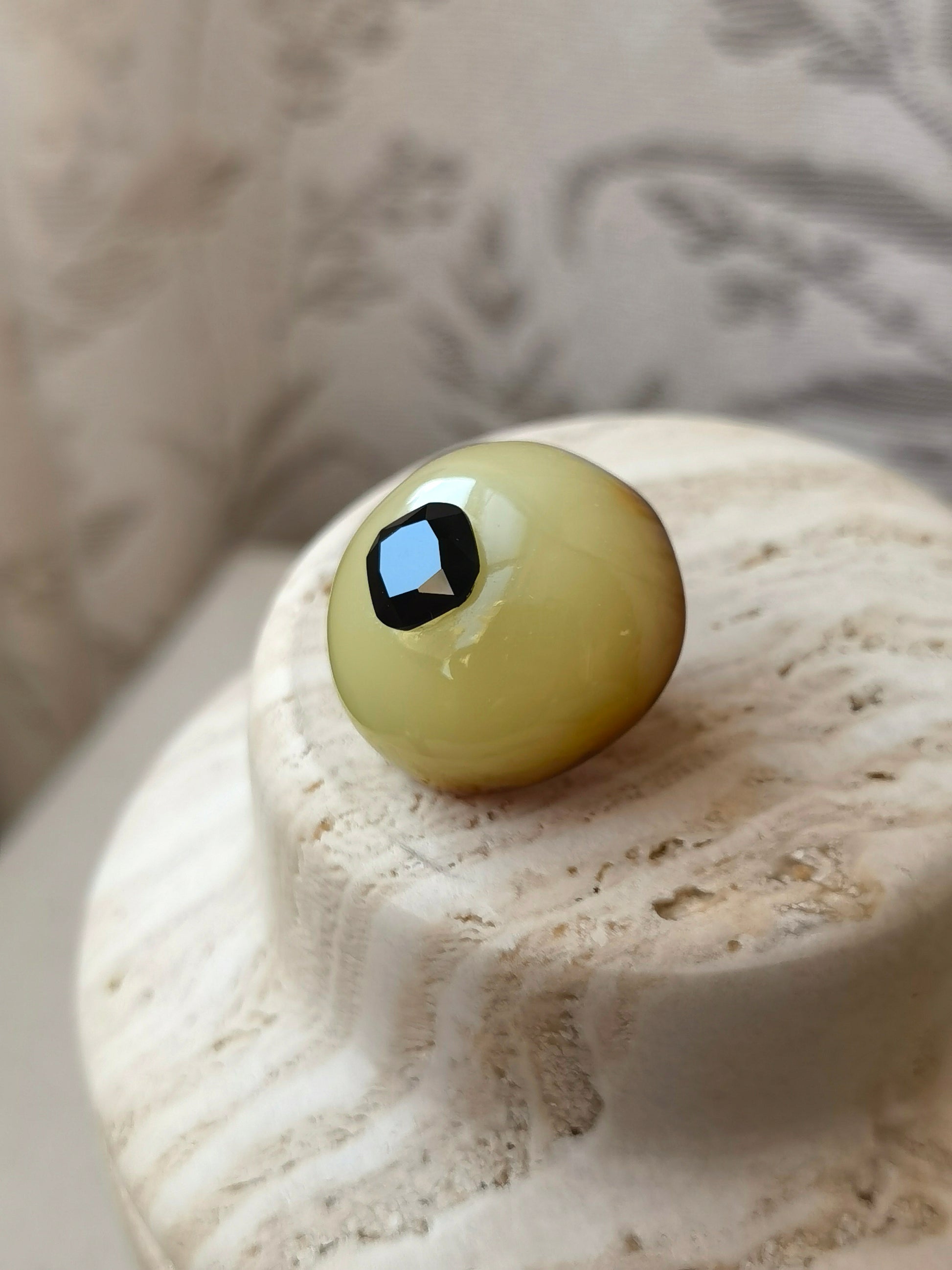 Handcrafted amber brooch featuring a cushion cut black spinel set in natural beeswax amber, creating a mysterious and artistic jewelry piece.