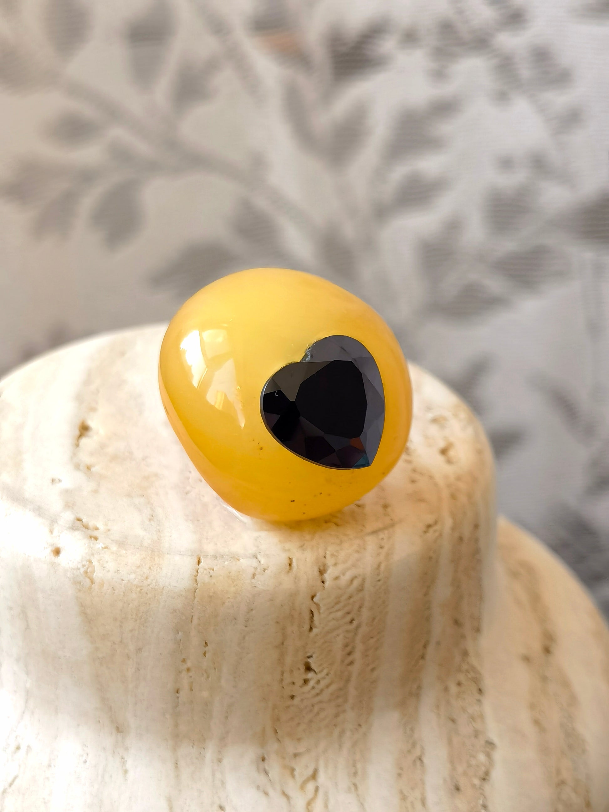 Natural beeswax amber brooch with a faceted heart shaped black spinel, highlighting organic texture and quiet contrast.