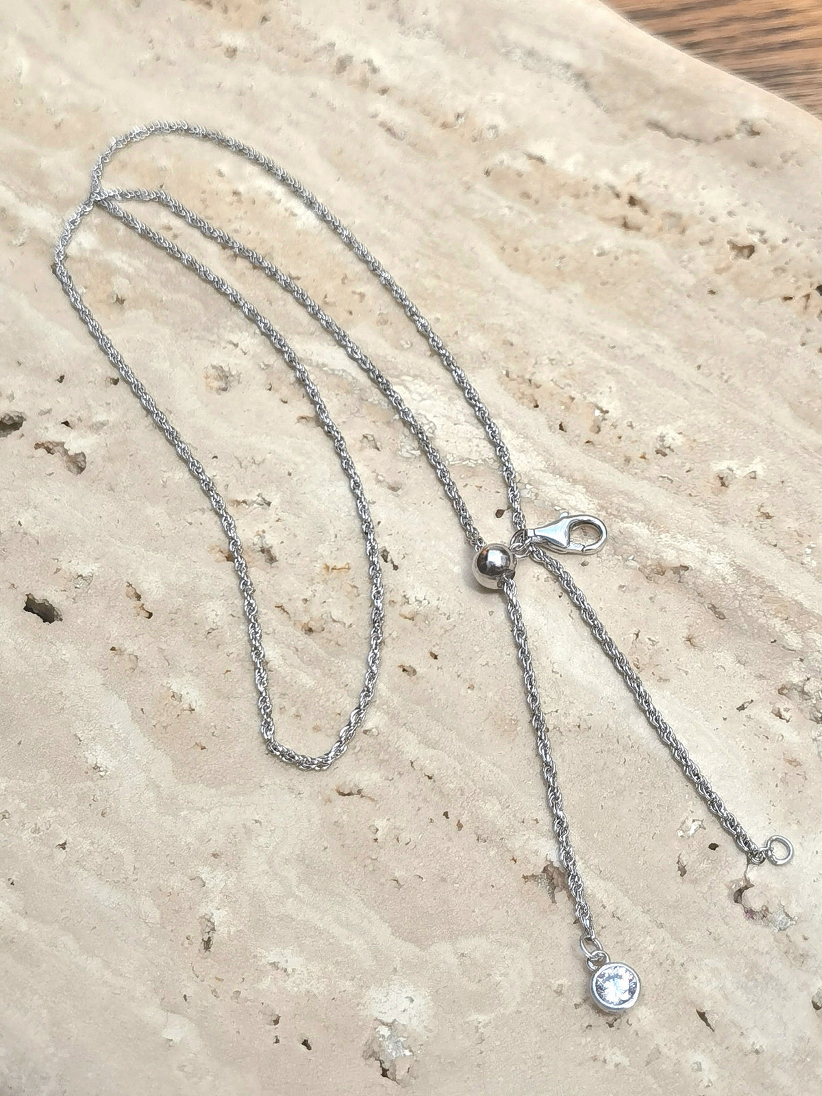 Natural Floral Amber & Matte Silver Necklace — Silver necklace with a clasp on a textured beige surface