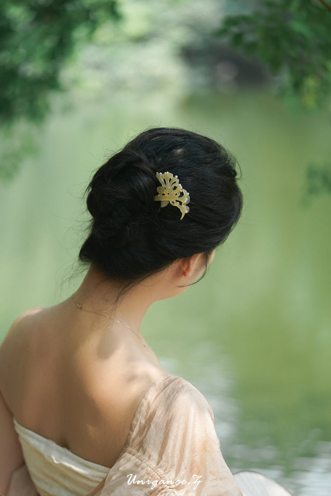 Woman with elegant hair accessory sitting by a serene water body
